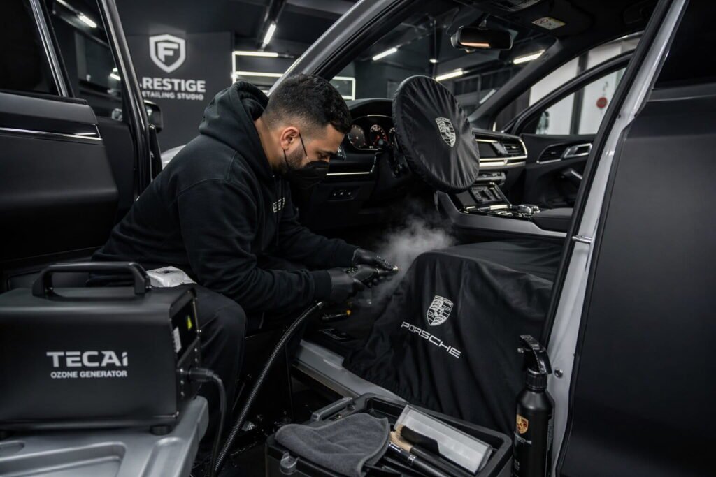 Car detailing expert performing ozone treatment and deep cleaning inside vehicle to remove bad smell permanently